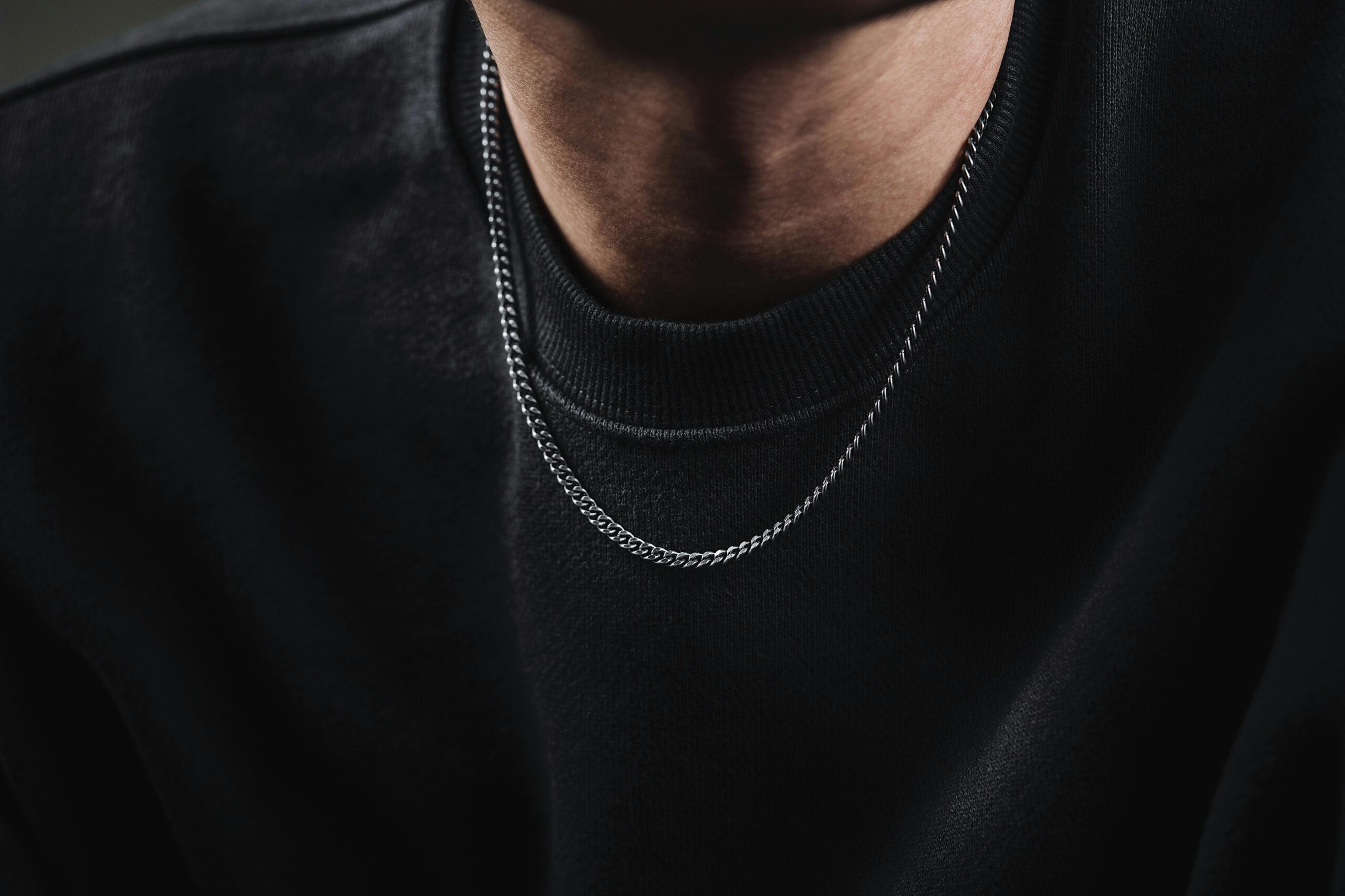 Stylish close-up of a silver chain necklace on a black t-shirt. Perfect for fashion and jewelry themes.